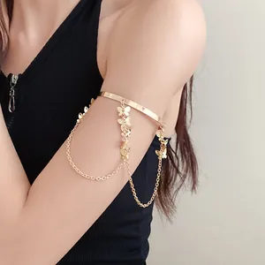 Vue détaillée d'un bracelet de bras doré à pompons papillons sur le bras d'un modèle
