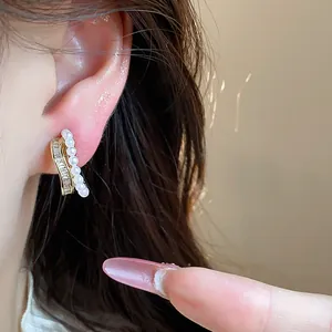 Close-up of elegant 18k gold plated zircon and pearl ear clip worn on a model's ear.