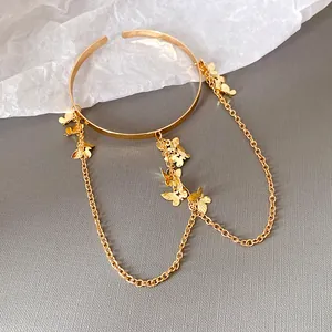 Gros plan d'un élégant bracelet papillon en métal doré avec des chaînes pendantes.