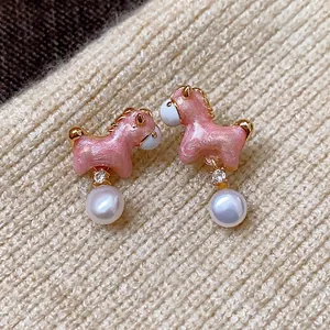 Pendientes de poni rosa con perlas y circón sobre fondo de punto beige.