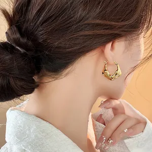 Close-up showing the intricate pleated texture of gold-plated hoop earrings on a model