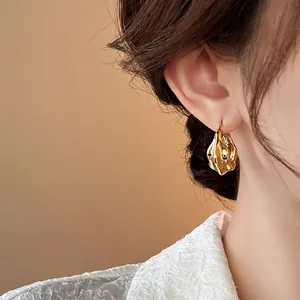 Close-up detail of elegant gold-plated wrinkled hoop earrings for a stylish look.
