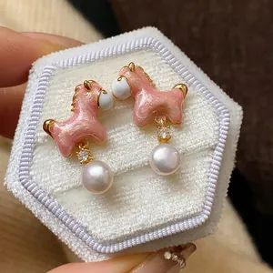 Primer plano de elegantes pendientes de poni de esmalte rosa con perlas y circón