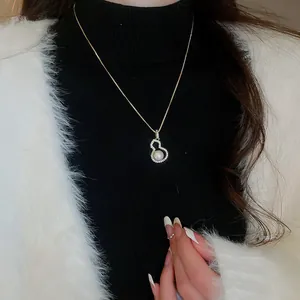Close-up of gold Hulu pendant necklace with pearl and sparkling rhinestones.