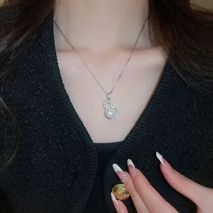 Close-up of elegant gourd pendant necklace with pearl and crystals on model neck