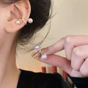 Close-up of gold and silver-plated pearl ear cuffs with cubic zirconia inlay