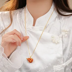 Elegant red enamel gourd pendant necklace worn on a traditional white Chinese garment.