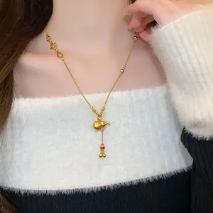 Close-up detail of a delicate gold-colored gourd pendant necklace worn on the neck