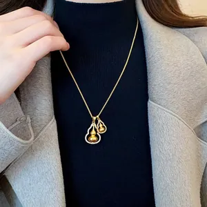 Elegant gold-tone double gourd necklace with sparkling stone accents shown on a female model