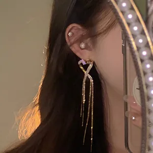 Detailed macro view of a luxury sparkling rhinestone heart tassel earring on model ear