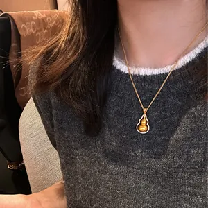 Close-up of a golden hulu gourd pendant necklace worn on an elegant female model in detail