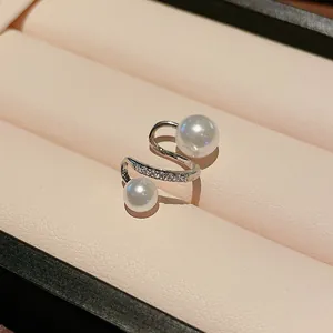 Detail view of a silver S-shaped ear cuff with two pearls and zircon accents