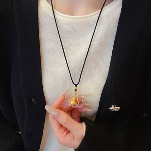Close-up of a delicate gold gourd pendant necklace on a model with elegant attire