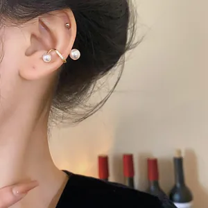 Detail showing an elegant gold-plated ear cuff with pearls and zircon on a model's ear.