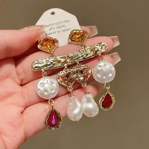 Close-up detail of vintage style gold-tone tassel earrings with pearls and red crystals