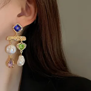 Detail of vintage earrings with colorful crystals and baroque pearls on a model's ear