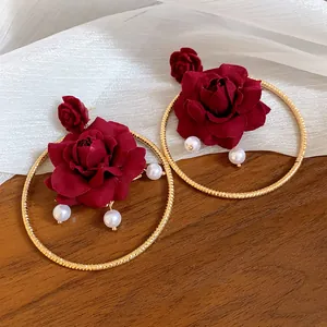 Close-up detail of vintage French style gold hoop earrings featuring deep red roses and pearls