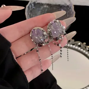 Detailed macro view of purple oval crystal earrings with elegant silver tassel chains