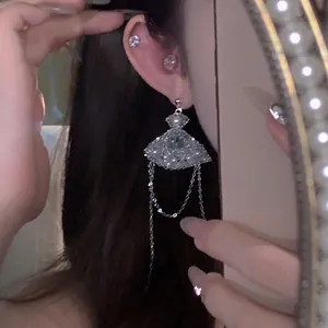 Close-up view of elegant silver fan-shaped tassel earrings with rhinestones worn on ear.