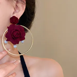 Close-up detail of vintage burgundy rose hoop earrings with pearls and gold finish