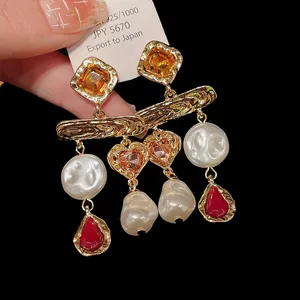 Detailed macro view of vintage style earrings featuring pearls and amber heart crystals