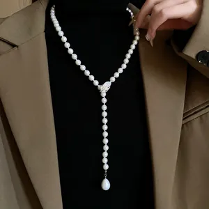 Detalle de un collar de perlas en Y de estilo francés con pluma de circonita en una modelo.