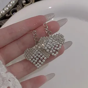 Detailed view of silver-toned earrings with imitation pearls and shimmering rhinestones.