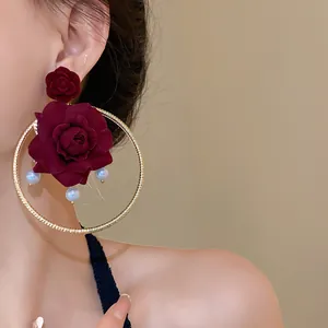 Close-up detail of vintage burgundy rose hoop earrings with pearls on an Asian model