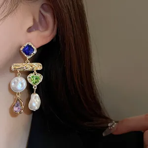 Close-up view of vintage gold-plated earrings with colorful gems and baroque pearls