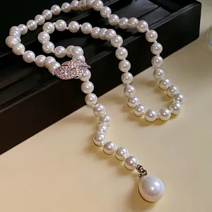 Detalle de collar de perlas con cierre de hoja en circonita y colgante de gota