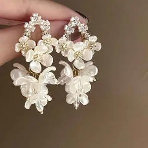 Close-up of elegant white pearl flower drop earrings with delicate rhinestone details