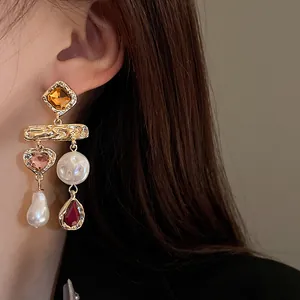 Close-up of vintage gold earrings with heart gems and baroque pearls