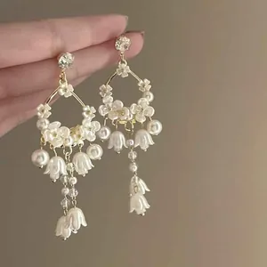Detailed view of elegant white floral drop earrings with pearls and gold accents