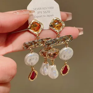 Detailed view of vintage gold-tone earrings with pearls, crystals and red drops.
