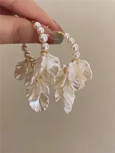 Close-up detail of elegant pearl flower earrings with intricate white petal designs.