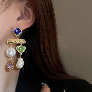 Close-up of vintage gold-tone tassel earrings with multicolored gems and baroque pearls