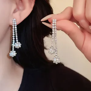 Stunning detailed view of elegant silver-toned rhinestone tassel earrings on ear and hand