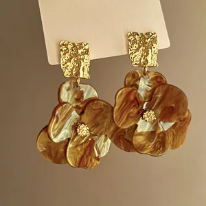 Close-up of elegant flower earrings with amber marble pattern and golden hammered studs