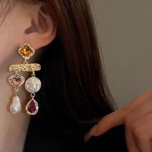 Detail view of vintage-style gold drop earrings with pearls and colorful rhinestones.