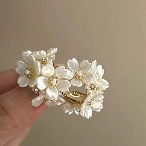 Close-up of elegant white pearl flower earrings with gold accents and sparkling stones
