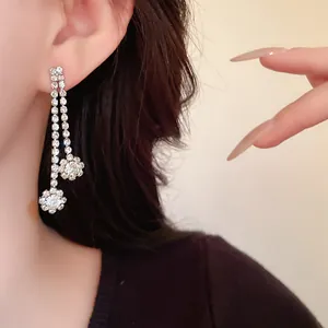 Close-up of elegant silver rhinestone tassel earrings with flower charms on model
