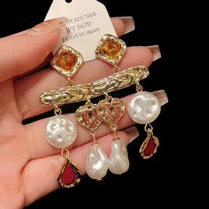 Close-up detail of vintage style gold earrings with heart crystals and baroque pearls