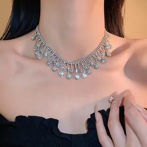 Close-up view of an elegant sparkling rhinestone tassel necklace on a model's neck.