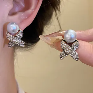 Close-up detail of elegant vintage French style white pearl and rhinestone criss-cross stud earrings