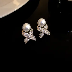 Macro view of French retro earrings featuring large pearl and rhinestone cross base detail