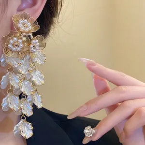 Boucles d'oreilles pendantes élégantes avec fleurs en perles et pétales blancs superposés.