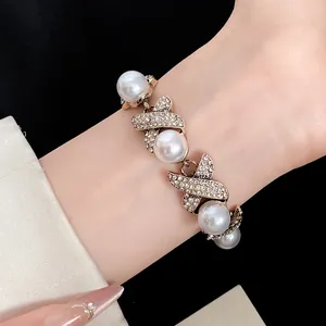Close-up of an elegant vintage gold-toned bracelet with pearls and rhinestones on a wrist.