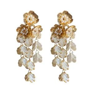 Élégantes boucles d'oreilles fleurs dorées avec perles et glands de pétales blancs.