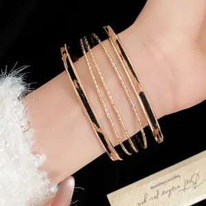 Close-up of gold bangle set with leopard print leather inlays on a wrist.