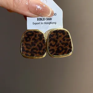 Gros plan détaillé de boucles d'oreilles floquées à motif léopard vintage avec bordure dorée